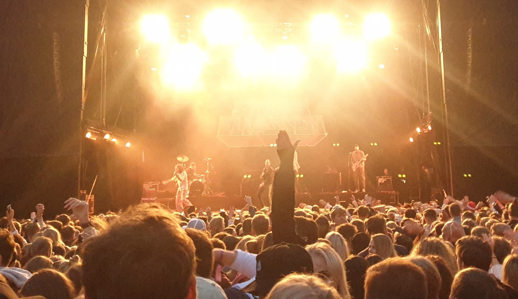 Bilde mot festivalscene, lyset går rett mot kamera og man ser bare bakhodene til publikum